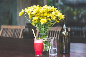 Yellow Daises in Clear Glass Vase Beside Bottle
