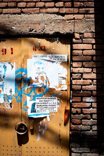Yellow door with old posters, graffiti tags and shadows
