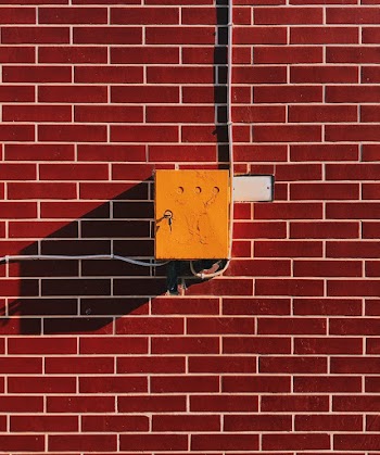 Yellow Electric Box on Brown Brick Wall