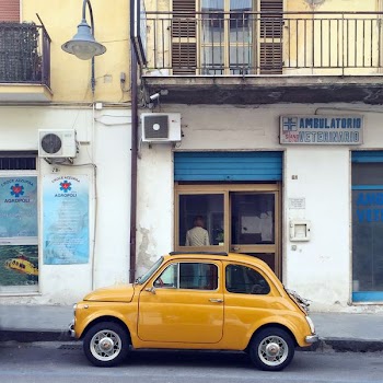 yellow Volkswagen Beetle in front of concrete building