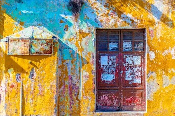 yellow, white, and teal painted concrete wall with red wooden 2-door window