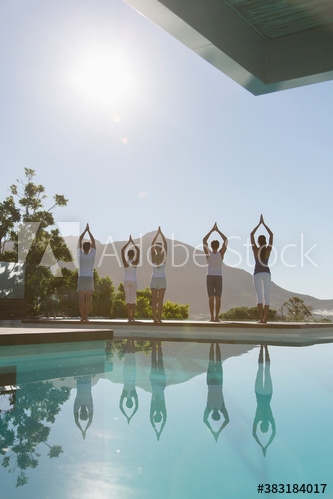 Yoga class practicing at sunny poolside