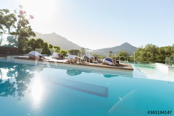 Yoga class practicing childs pose at sunny poolside