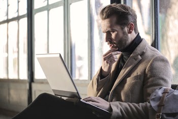  Young Adult Man looking seriously on laptop screen while sitting 