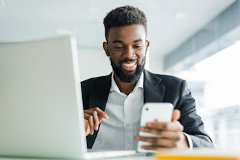 Young african american business man using phone and making winner gesture with fist in office Free Photo