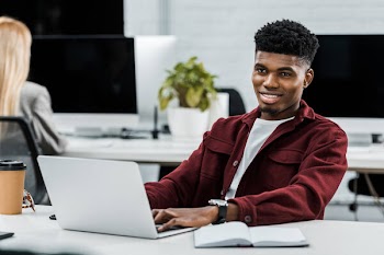 Young african american businessman at workplace with laptop in office