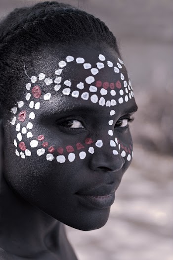 Young African girl, tribal painted face in white and red, partial desaturated