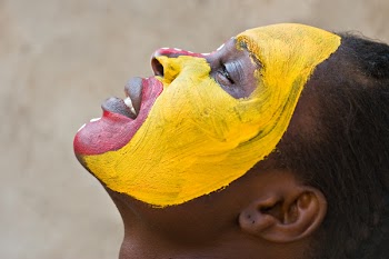Young African girl, tribal painted face in yellow and red, harmonic triangles use it portrait or landscape