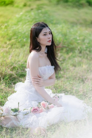 Young Brunette in a White Dress Sitting on the Grass