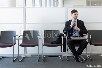 Young businessman adjusting necktie in office lobby