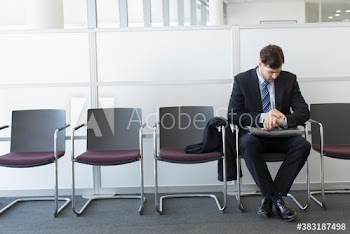 Young businessman checking time on wristwatch in office lobby