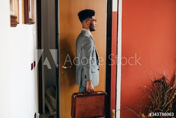 Young businessman holding briefcase standing at doorway