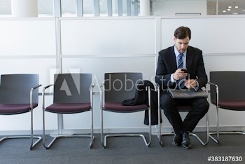 Young businessman using smart phone in office lobby