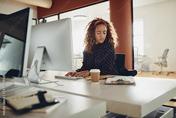 Young businesswoman reading notes at her office workstation
