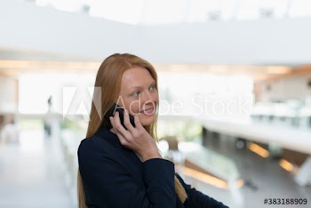 Young businesswoman talking on smart phone in office