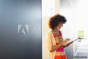Young businesswoman using digital tablet in office corridor