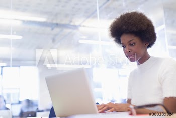 Young businesswoman with afro working at laptop in office