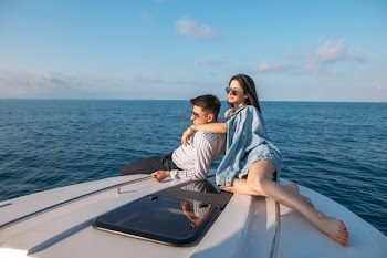 Young caucasian couple in love relaxing on yacht bow over beautiful seascapes with copyspace for advirtising. Main focus on sea scape with blue sky and horizon line
