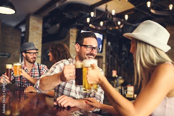 Young cheerful people in the beer pub drinking and having good time. Friendship concept with young people enjoying time together and having genuine fun at cool vintage pub 