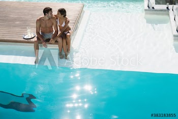 Young couple relaxing at sunny swimming pool