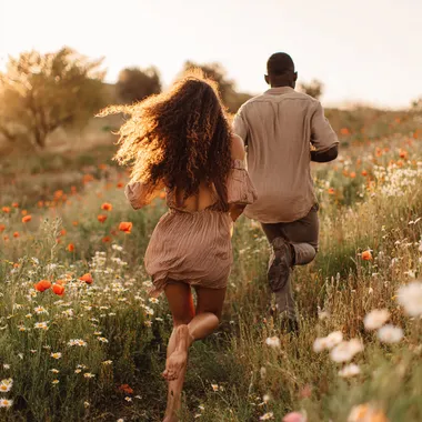 Young Couple Running Through Wildflower Meadow