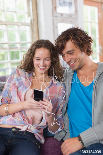Young couple sharing headphones listening to music