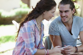 Young couple sharing headphones listening to music