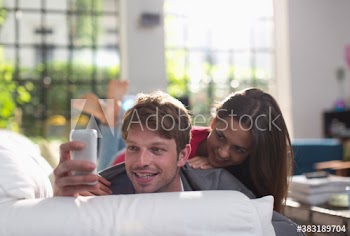 Young couple taking selfie with smart phone on sofa