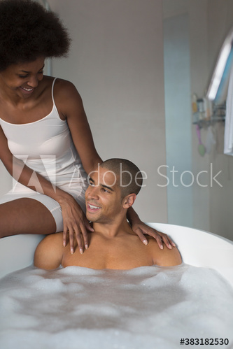 Young couple talking and enjoying bubble bath in bathroom