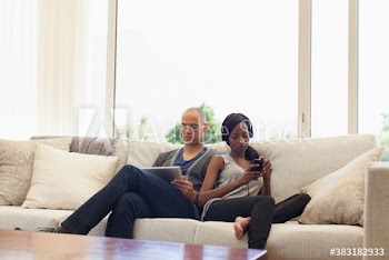 Young couple using digital tablet and listening to music on sofa