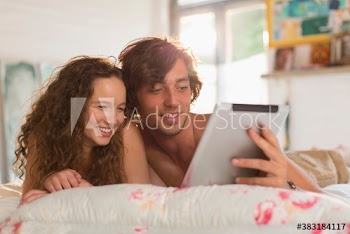 Young couple using digital tablet on bed