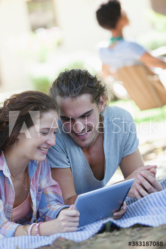 Young couple using digital tablet on blanket