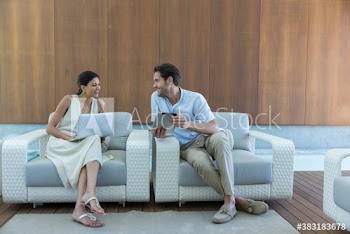 Young couple using laptop and digital tablet in armchairs