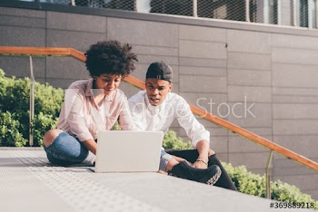 Young couple using laptop while sitting on staircase