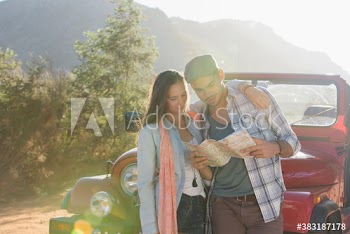 Young couple with map outside sunny jeep