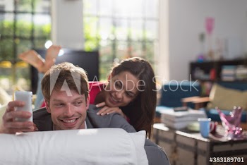 Young couple with smart phone on sofa