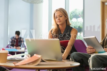 Young female college student studying at laptop in student lounge
