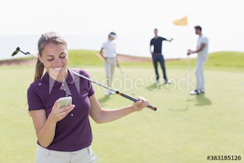 Young female golfer using smart phone on golf course