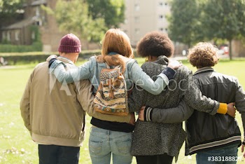 Young friends hugging and walking in sunny park
