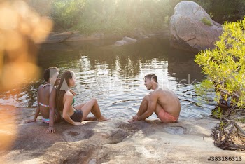 Young friends in bathing suits hanging out at sunny lakeside