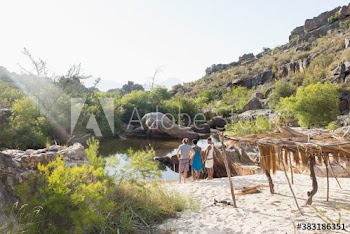 Young friends on sunny beach below rocks