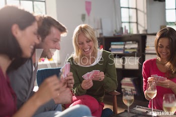 Young friends playing cards and drinking wine
