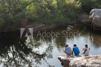 Young friends relaxing on rocks at lakeside