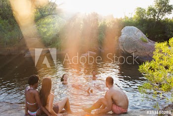 Young friends swimming and relaxing at sunny pond