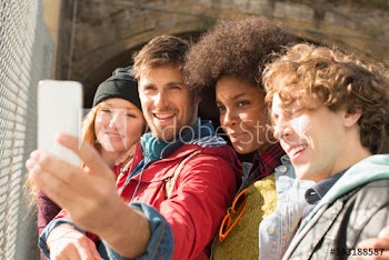 Young friends taking selfie at sunny fence