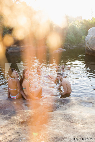 Young friends talking and swimming at pond