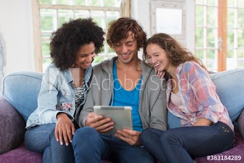 Young friends using digital tablet on sofa