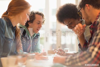 Young friends using smart phone in cafe