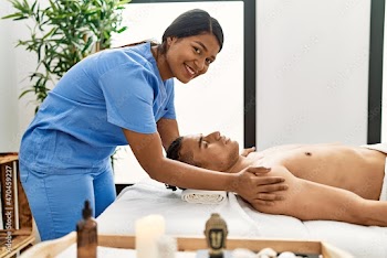 Young latin massage therapist woman giving relaxing treatment on man shoulders at beauty center.