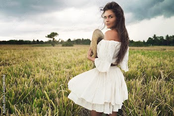 Young lovely woman holding straw hat in the rice field